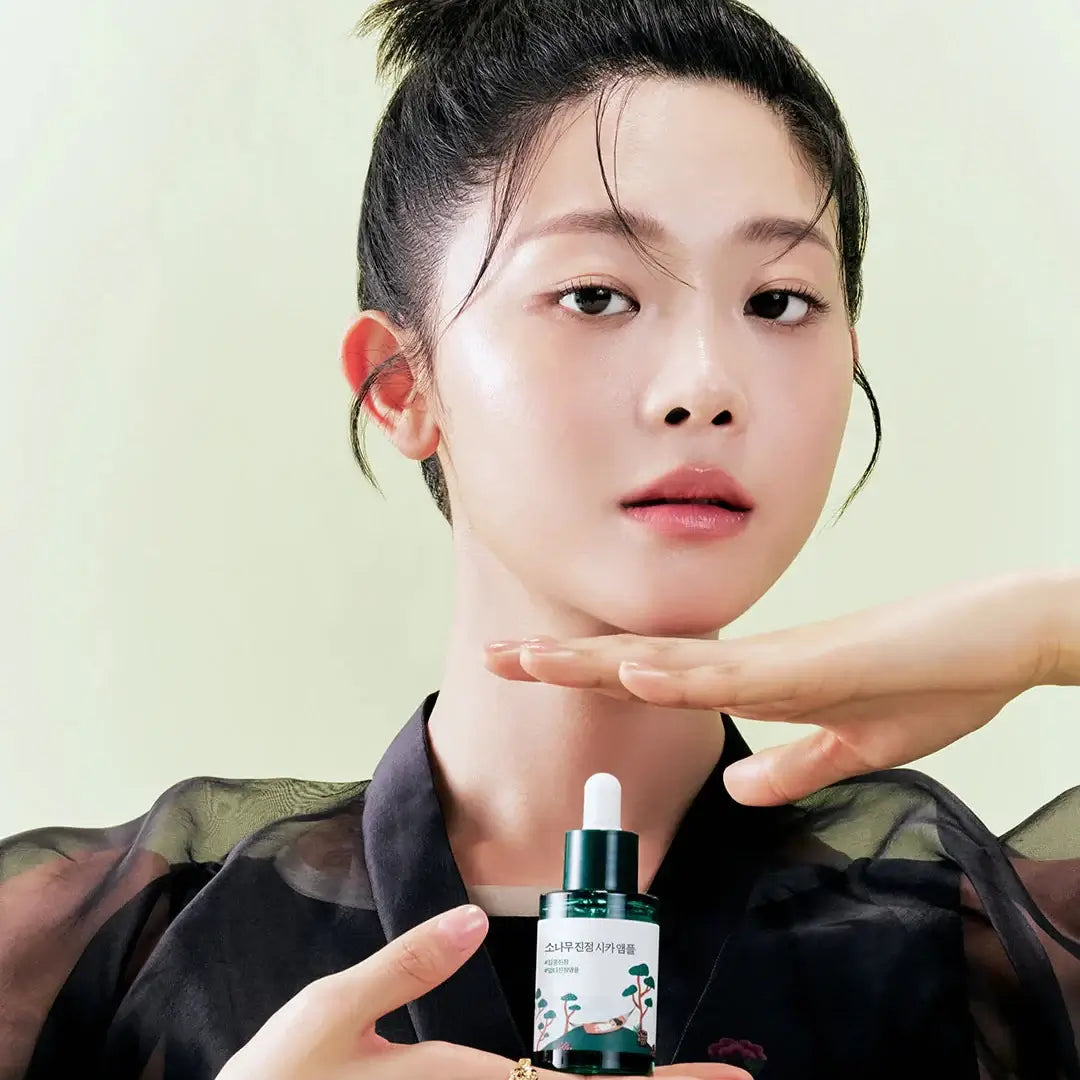 Woman holding ROUND LAB Pine Calming Cica Ampoule 30ml, highlighting skincare benefits.