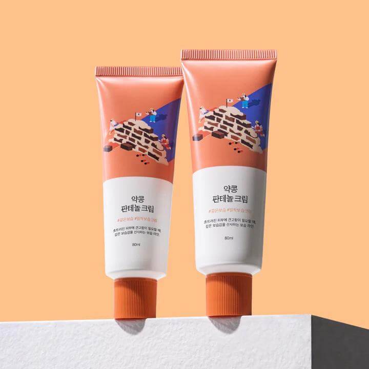 Two tubes of ROUND LAB Yakkong Panthenol Cream 80ml displayed on a white surface against a peach background.