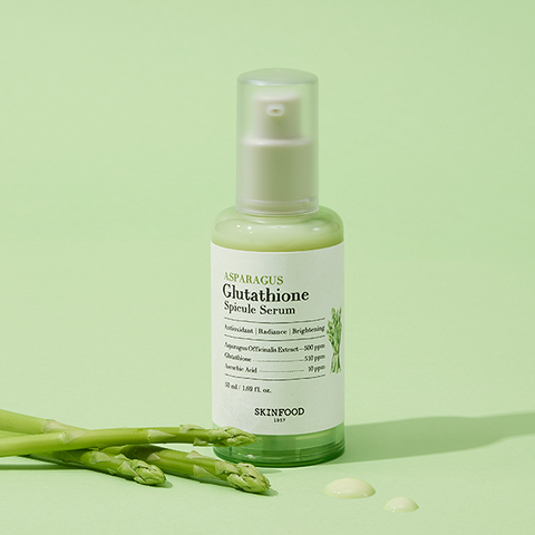 SKINFOOD Asparagus Glutathione Spicule Serum 50ml bottle on green background with asparagus