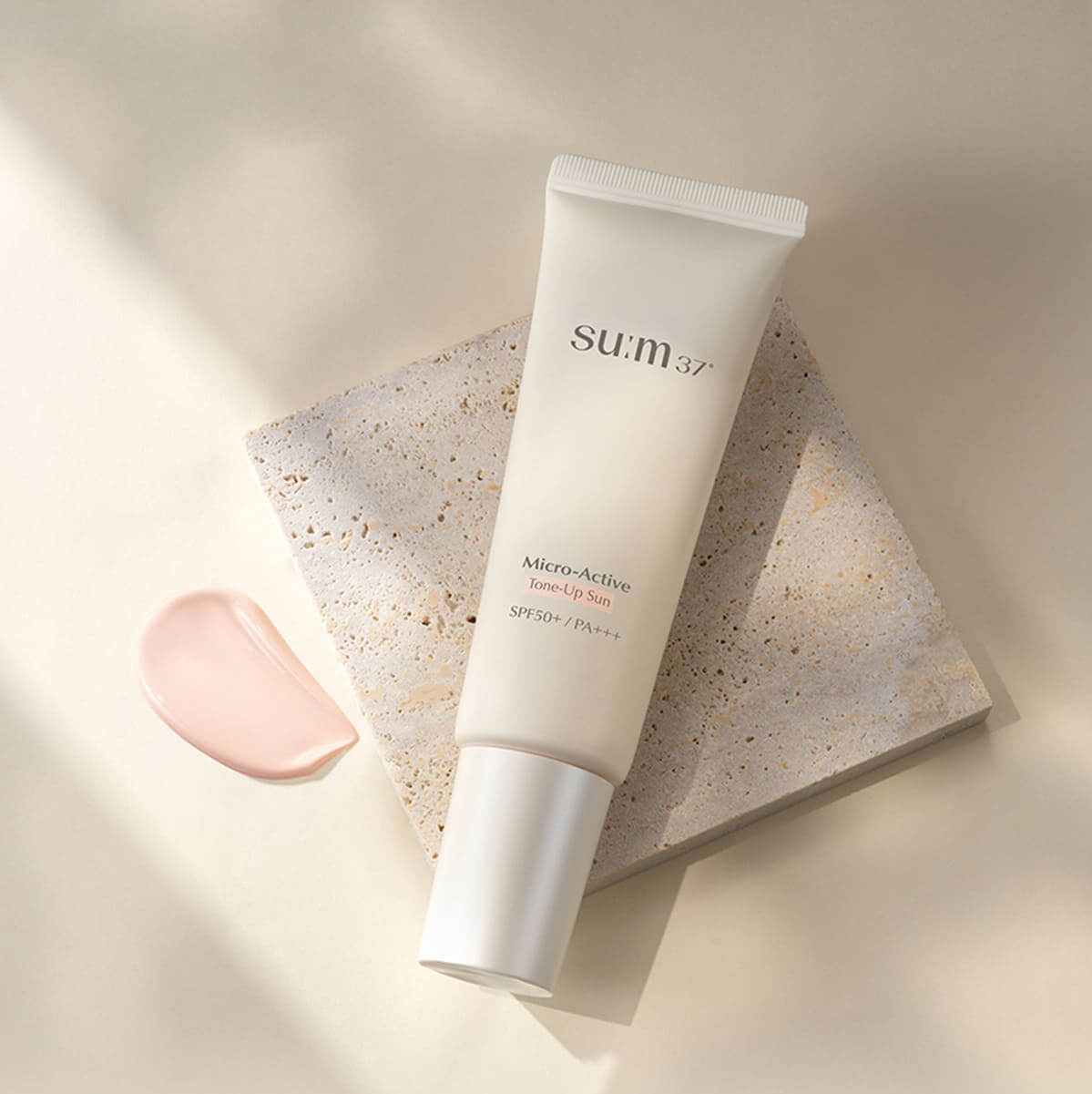 SU:M37 Microactive Tone Up Sun 50 SPF50+ / PA+++ tube on stone background with product swatch