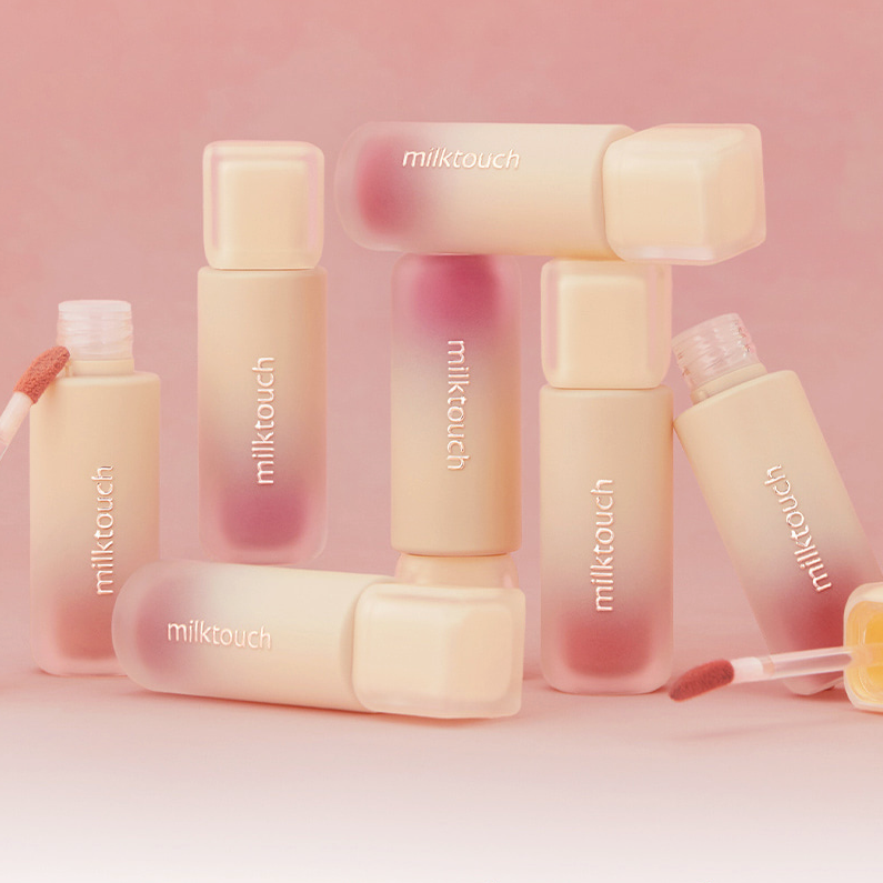 MILK TOUCH Spread Fit Blur Tint bottles arranged with applicators on a pink background.