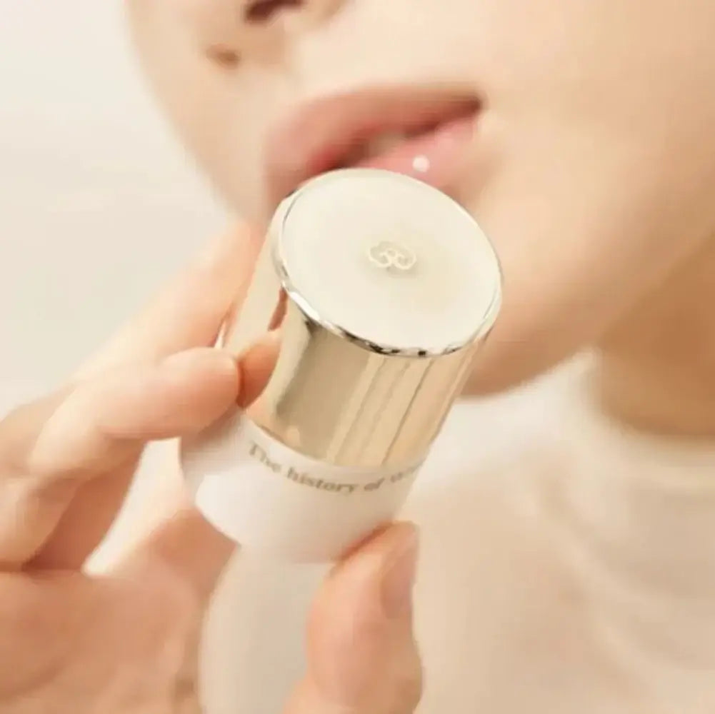 THE WHOO Royal Essential Golden Lip Serine 15ml held in hand near lips, showcasing luxurious lip care product.