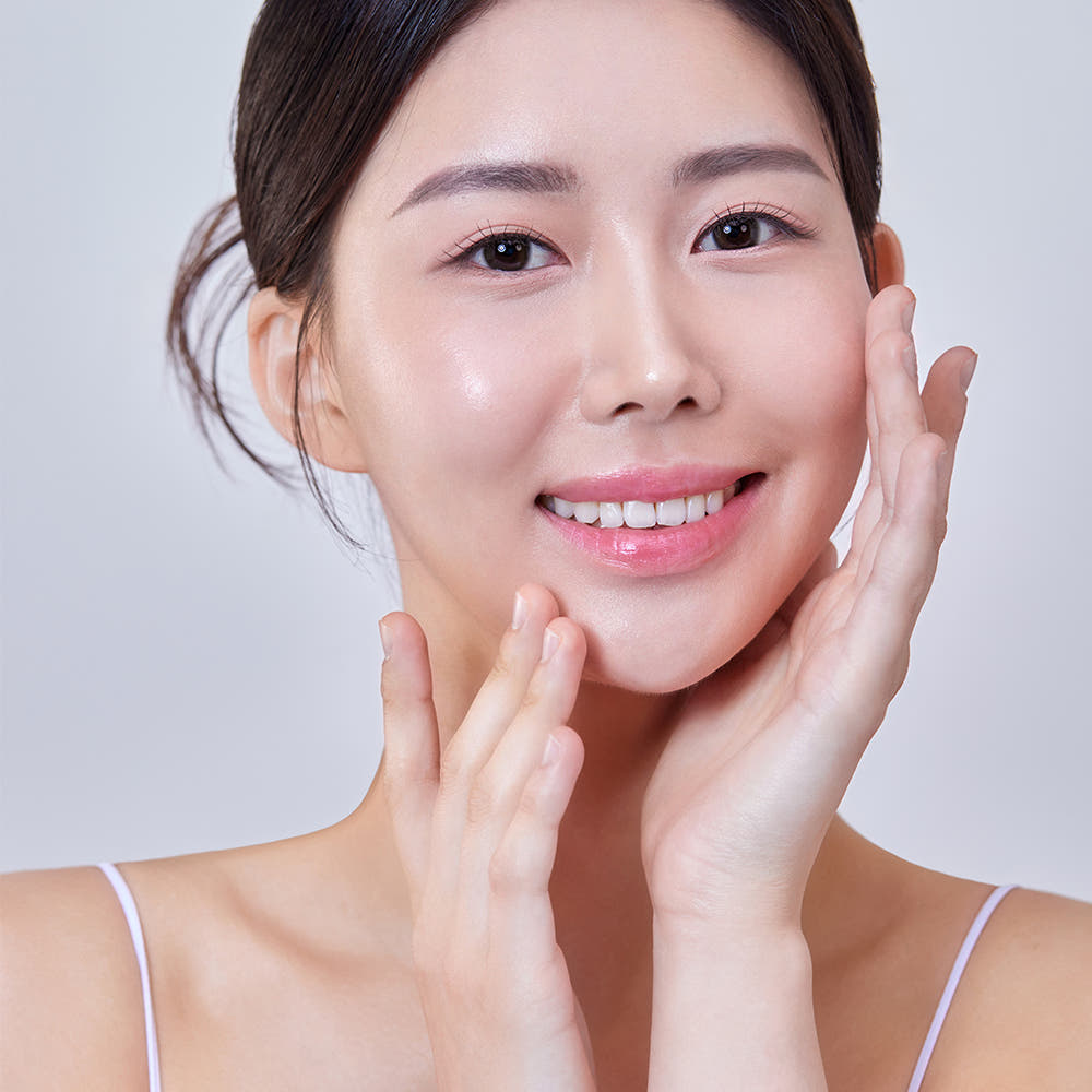 Smiling woman with clear skin, applying THE SAEM Temptation Age Return Eye Cream 30ml