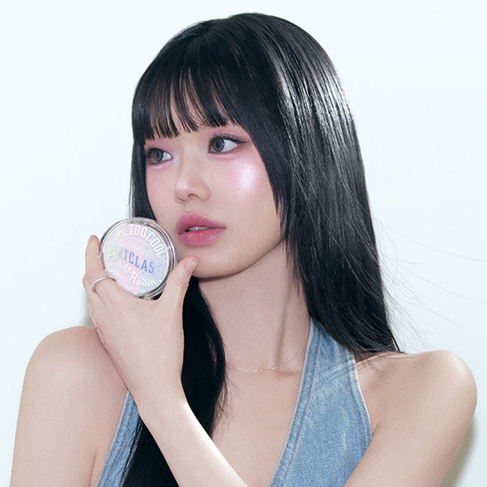 Model holding TOO COOL FOR SCHOOL Art Class By Rodin Highlighter with radiant makeup look