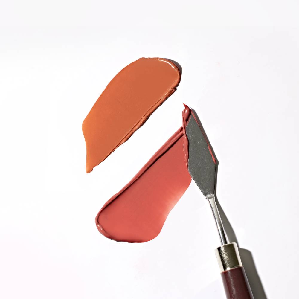 TOUCH IN SOL Vegan Again Juicy Plumping Lipstick swatches on white background with metal spatula.