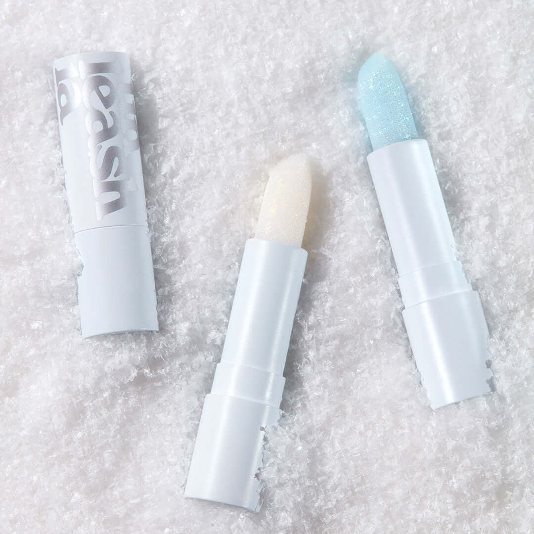 UNLEASHIA Glacier Vegan Lip Balm in snowy background showcasing two open lip balms with icy colors.