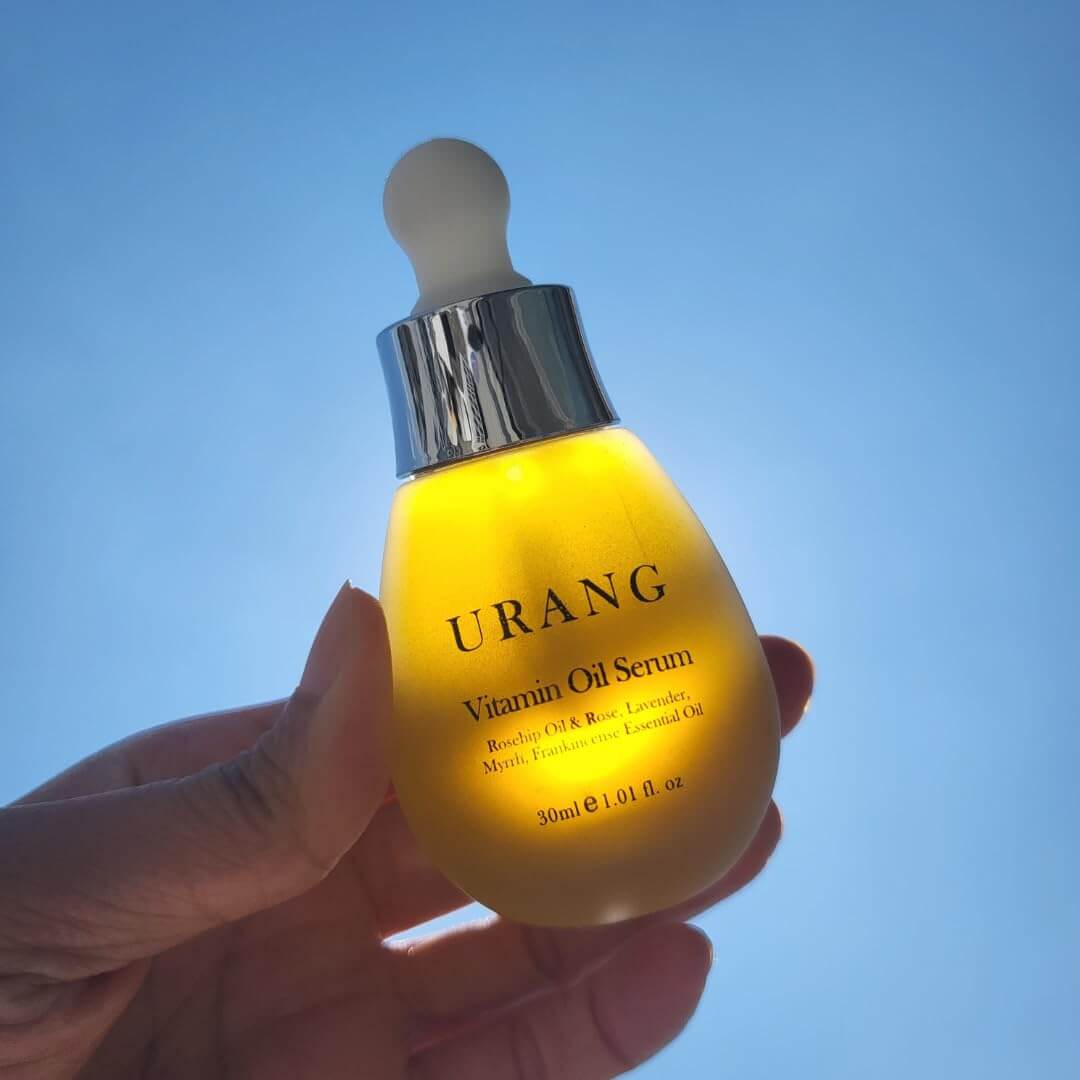 URANG Glow Oil Serum 30ml in sunlight showcasing luxurious skincare product in dropper bottle.