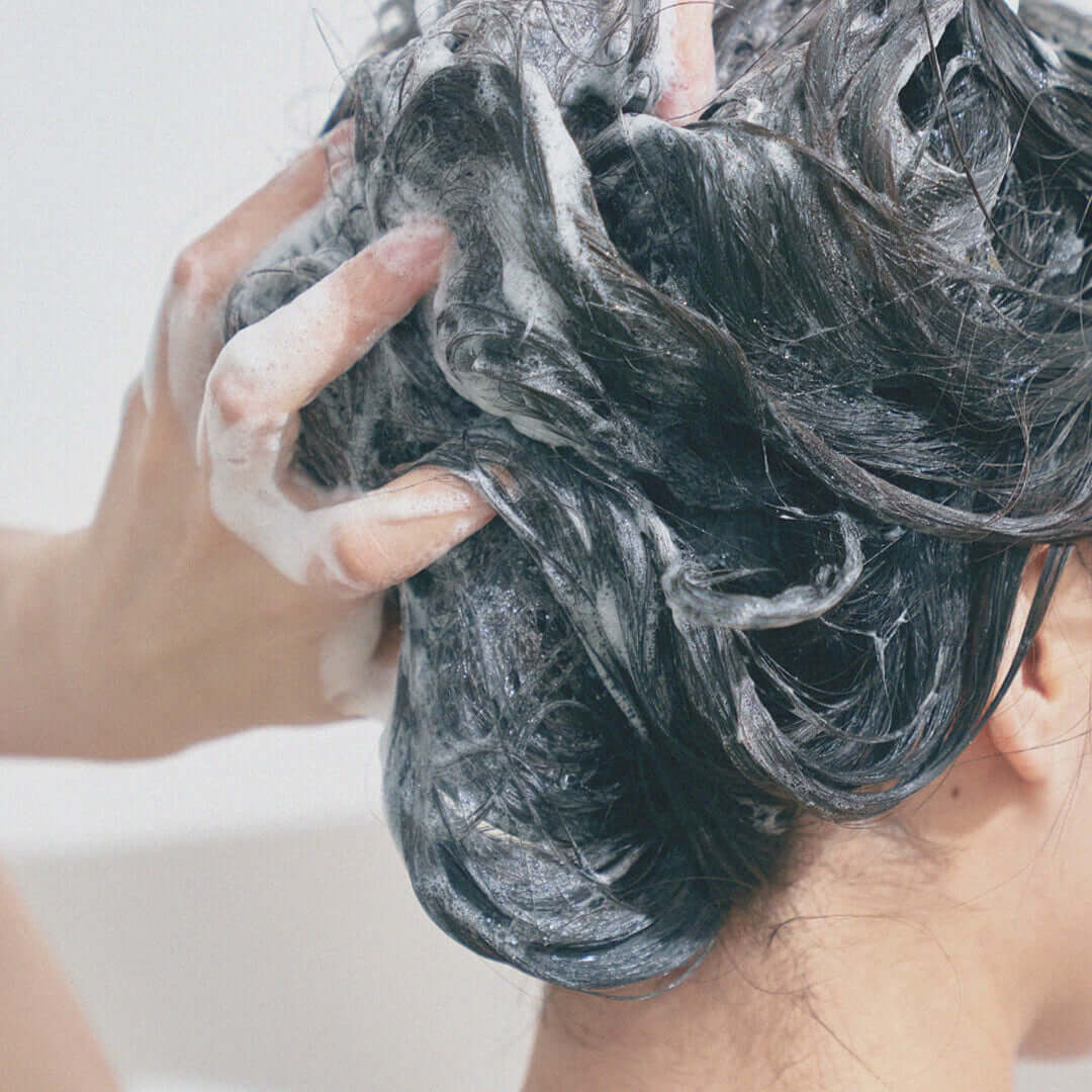 Person using URANG Moringa Scalp Strengthening Shampoo Bar, lathering and cleansing hair for healthy scalp and strong hair.