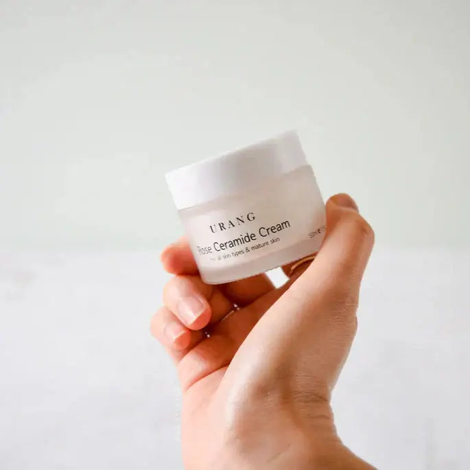 Hand holding a jar of URANG Rose Ceramide Cream 50ml, moisturizing cream for smooth skin