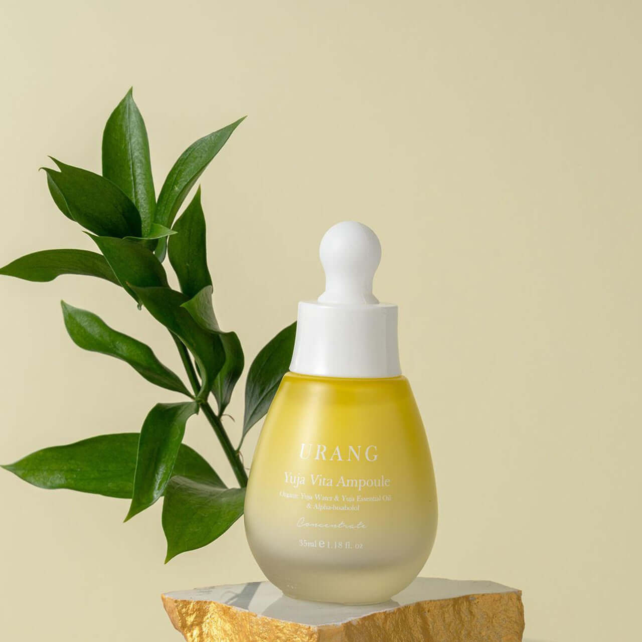 URANG Yuja Vita Ampoule bottle on a stone stand with plant background