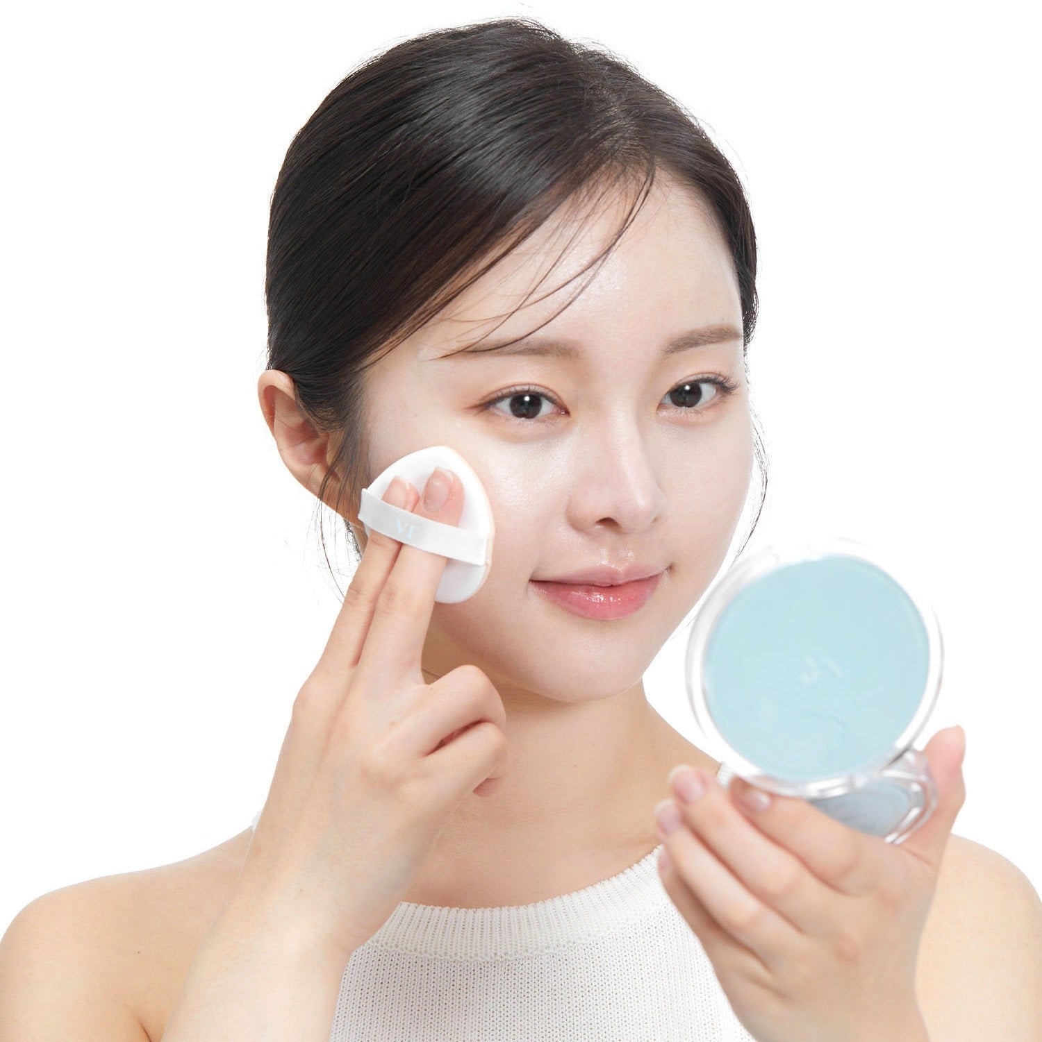 Woman applying VT COSMETIC PDRN Essennce Glow Sun Pact 10g with puff, using compact mirror for even application.