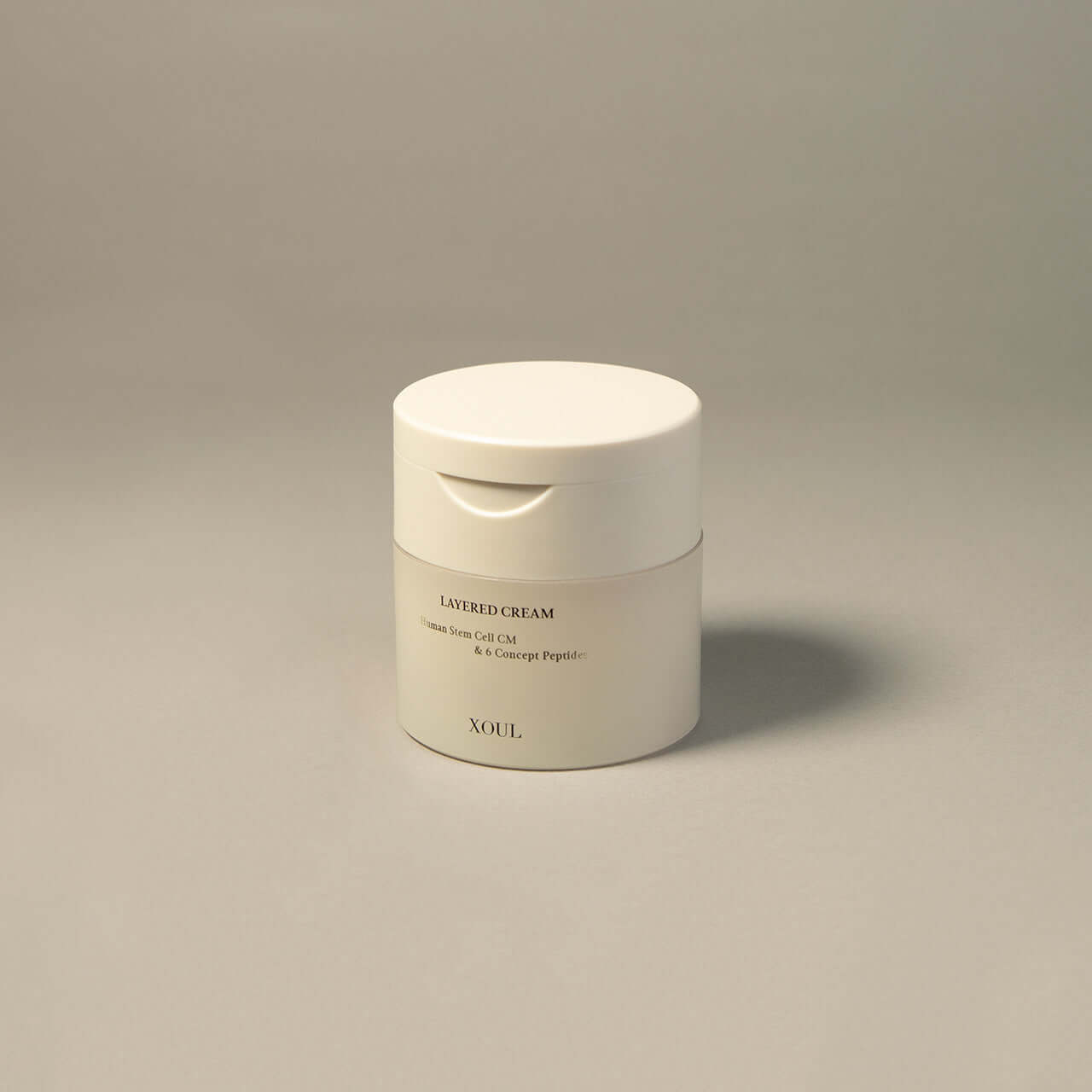 XOUL Layered Cream 50g white jar on gray background. Anti-aging skincare product with peptide formula.