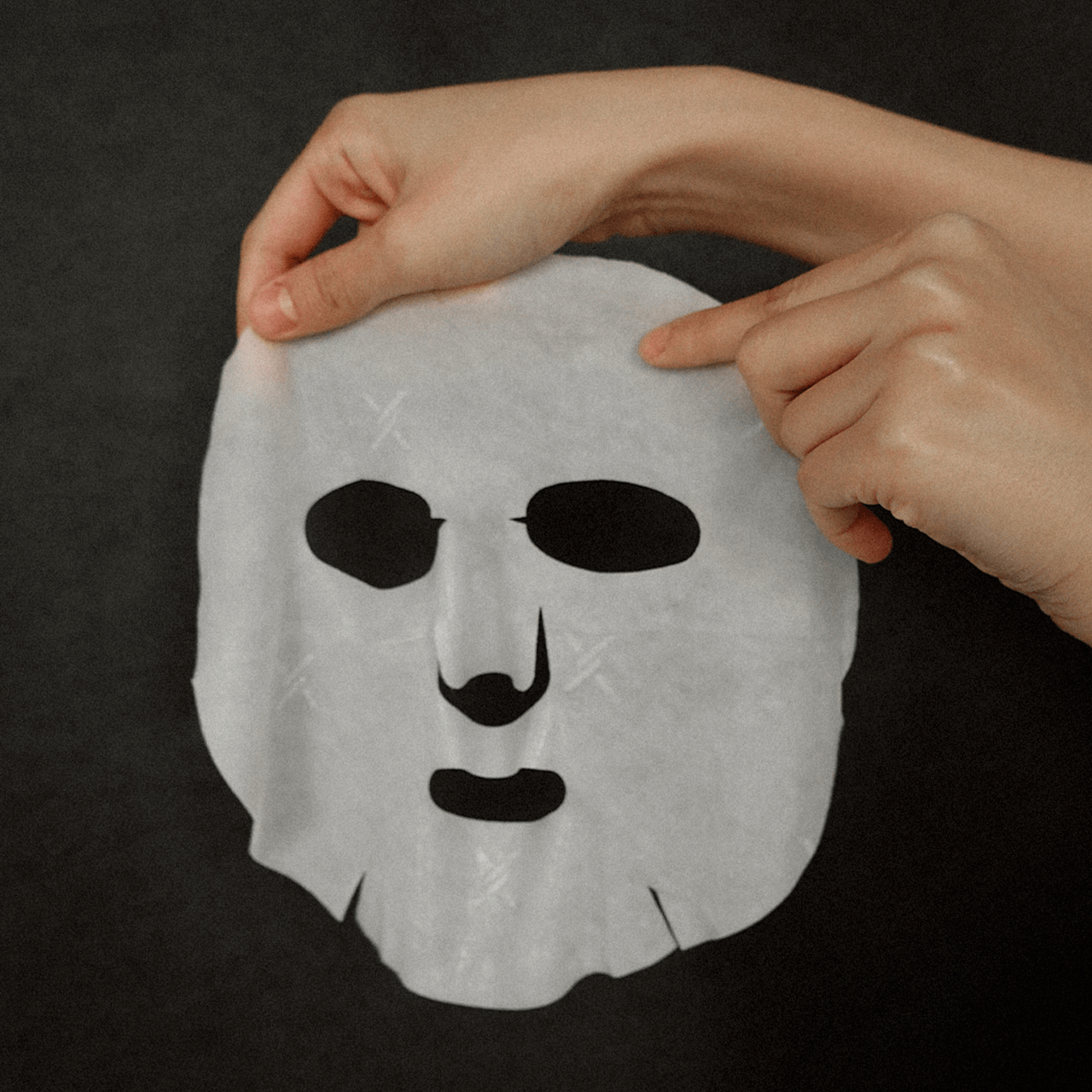 Person holding XOUL Secret Solution Cream Mask 15p against a dark background, showcasing its texture and design.