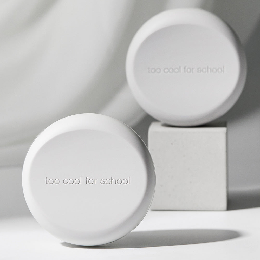 TOO COOL FOR SCHOOL Art Class Fixing Cover Cushion in minimalist packaging displayed on a pedestal.