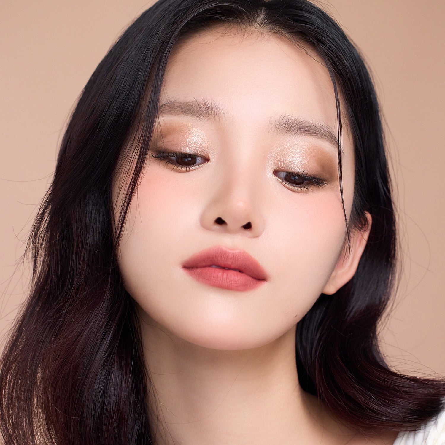 Model wearing DEAR DAHLIA Dream velvet Lip Cloud in warm lighting, showcasing lipstick's smooth texture and rich color on lips.