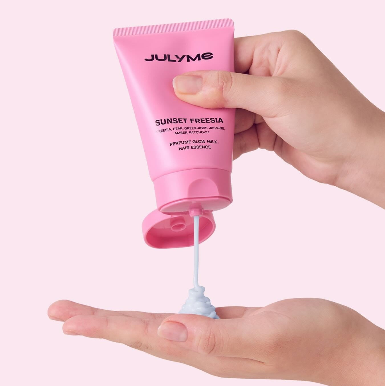 JULYME Perfume Glow Milk Hair Essence 80ml (Sunset Freesia) being dispensed into a hand from pink tube