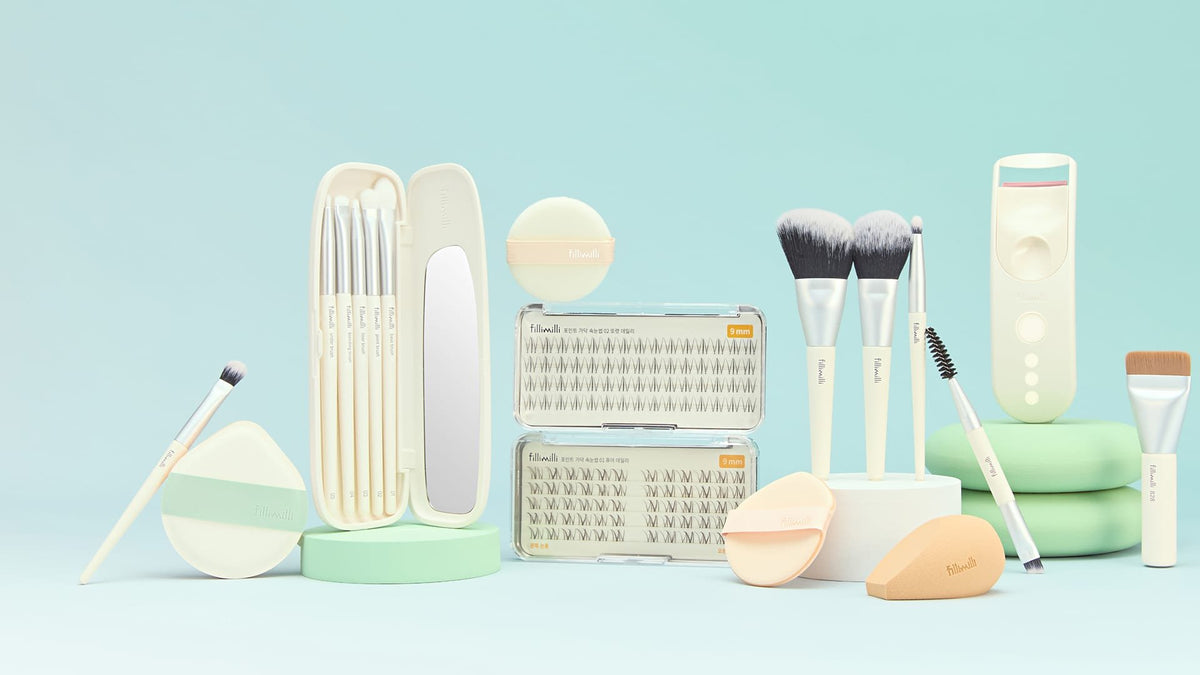 Fillimilli makeup brushes, puffs, strand lashes and a heated eyelash curler on a mint background