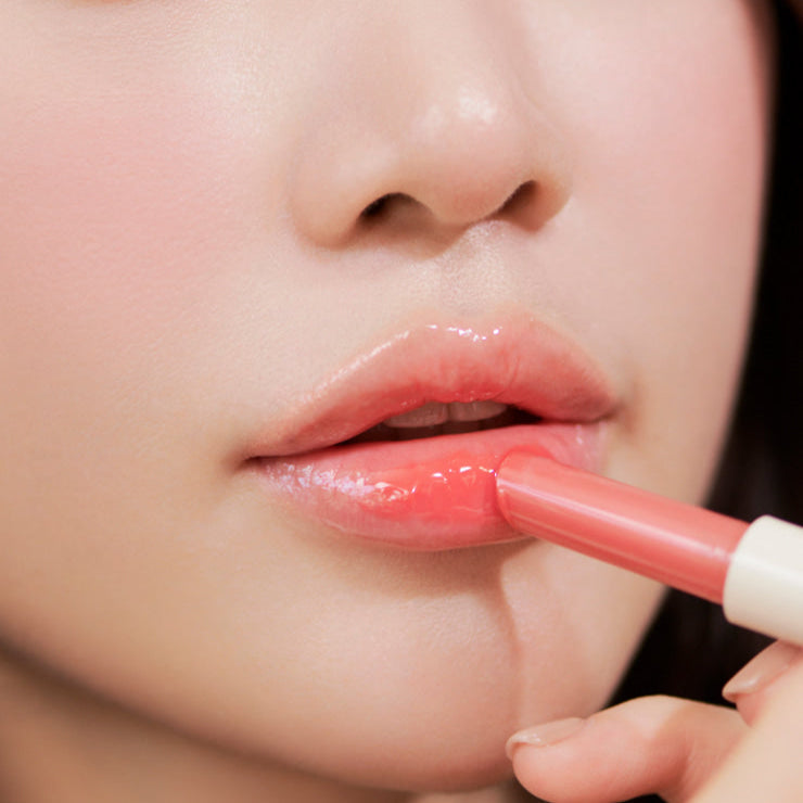 Close-up of a person applying pink lipstick, highlighting lip care and beauty.