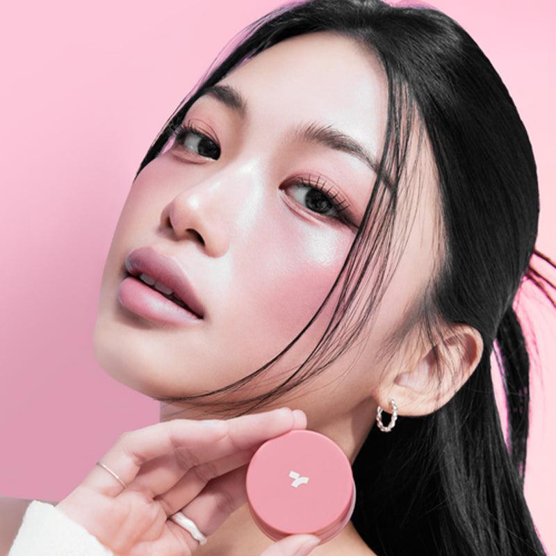 Woman holding TONY MOLY Cheek Tone Lip & Cheek Duo Balm against pink background