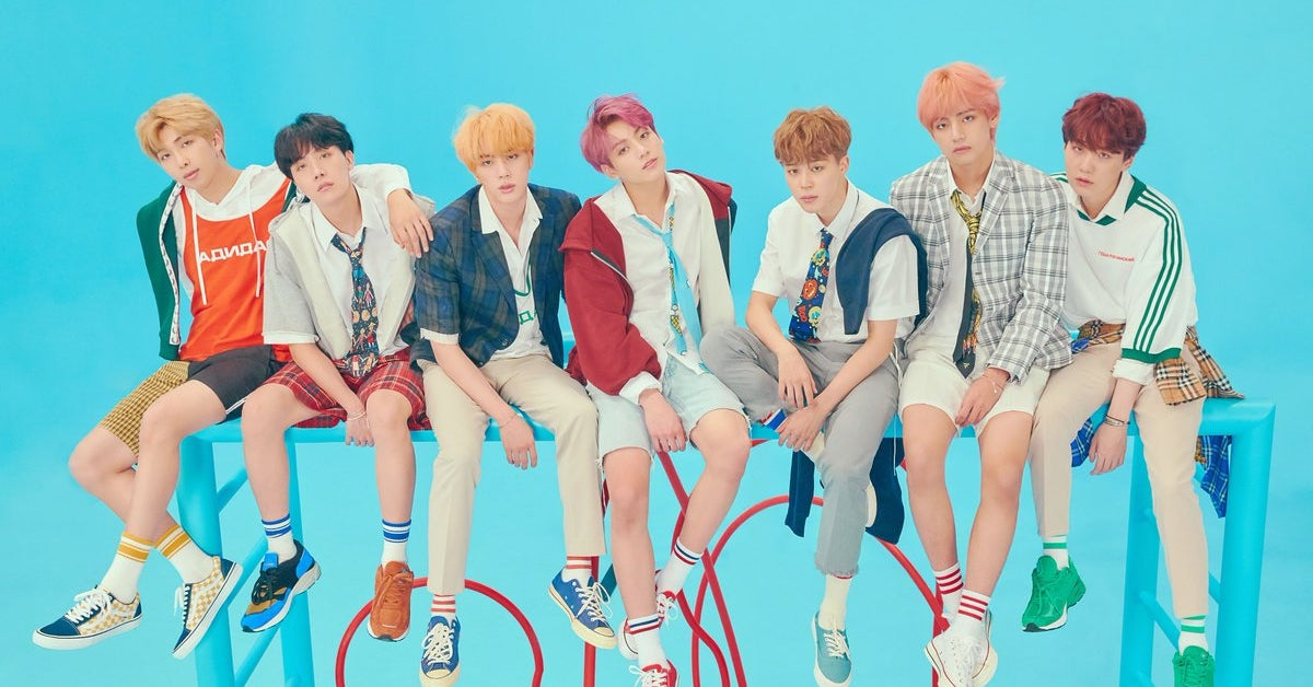 BTS The Legendary Trailblazers of K-Pop's Global Domination posing in colorful outfits against a blue background.