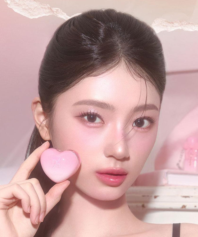 Person holding a heart-shaped beauty product, highlighting the DASIQUE Daisy Candy Rolling Pot aesthetics.