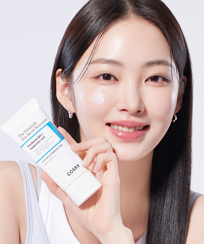 Woman applying COSRX The Ceramide Skin Barrier Moisturizer to her face, holding the product in hand.