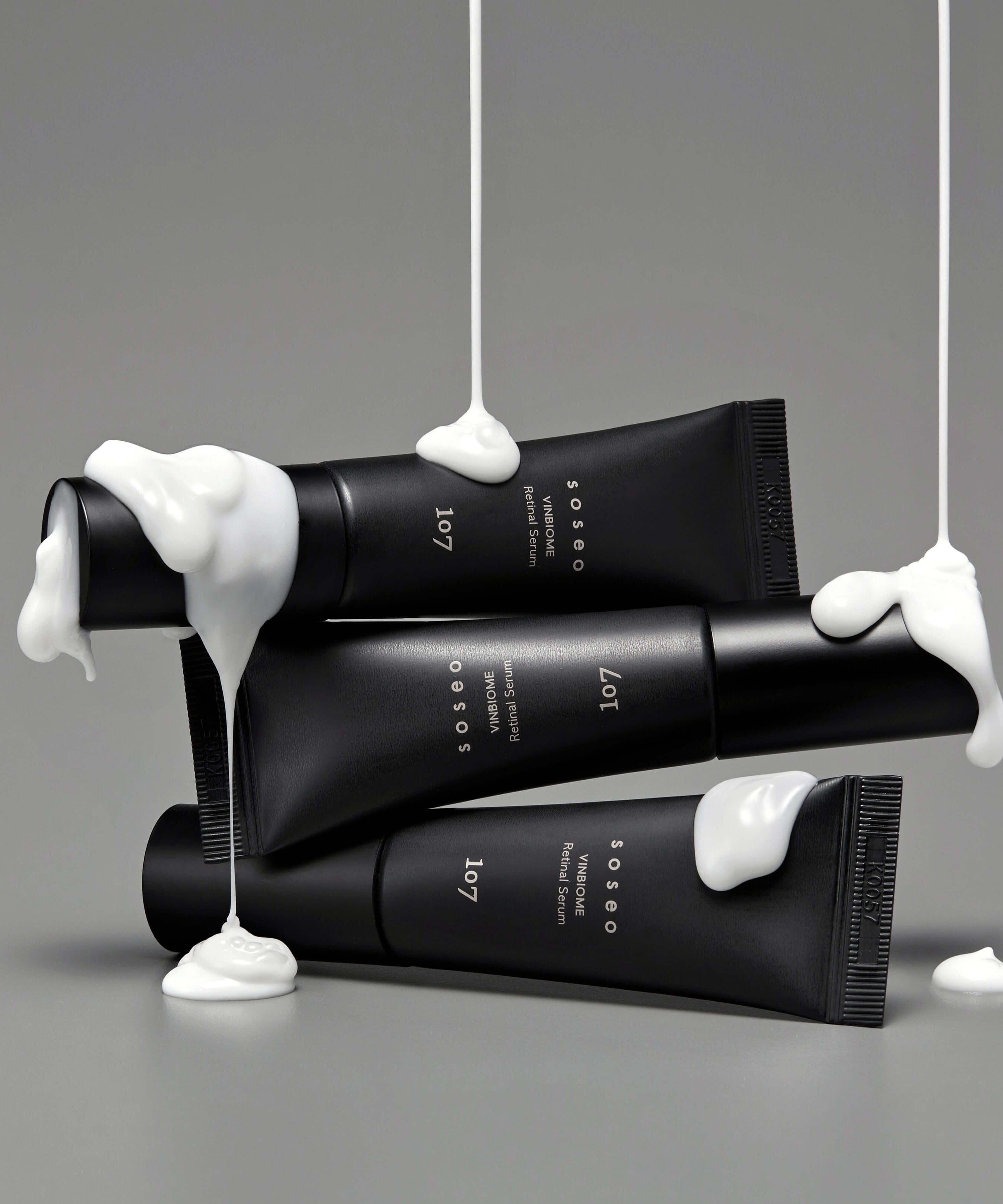 107 Soseo Vinbiome Retinal Serum 20ml on gray background with creamy texture drips, highlighting luxury skincare.