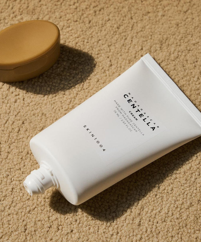 SKIN1004 Madagascar Centella Cream 75ml tube on textured background with cap beside it.