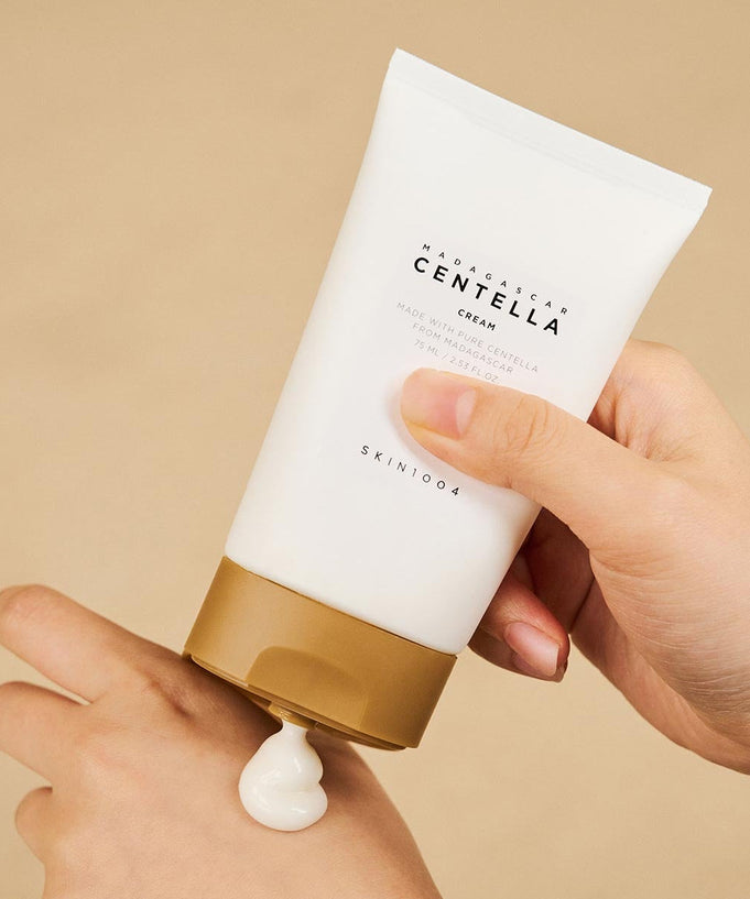 Person applying SKIN1004 Madagascar Centella Cream 75ml to hand, showcasing skincare product in use.