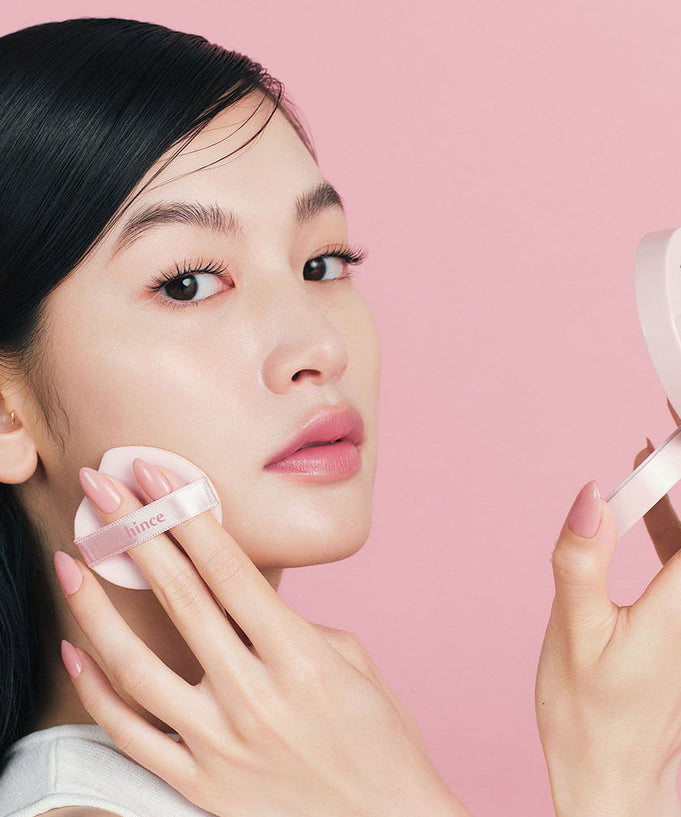 Model applying HINCE Cover Master Pink Cushion on face, showcasing radiant finish and smooth application for flawless skin.