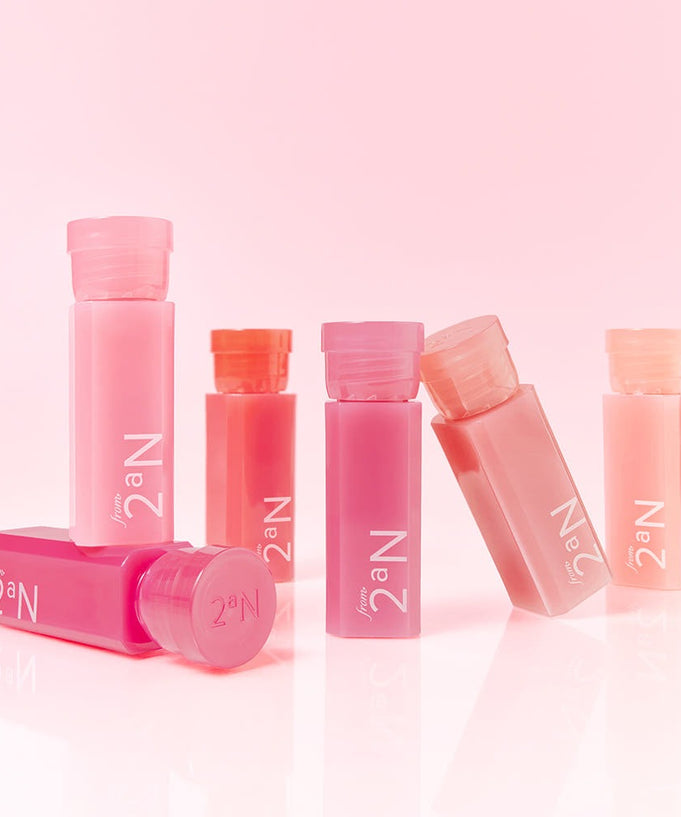 Collection of colorful 2an Mini Glaze Bouncing Tint bottles on a pink background.