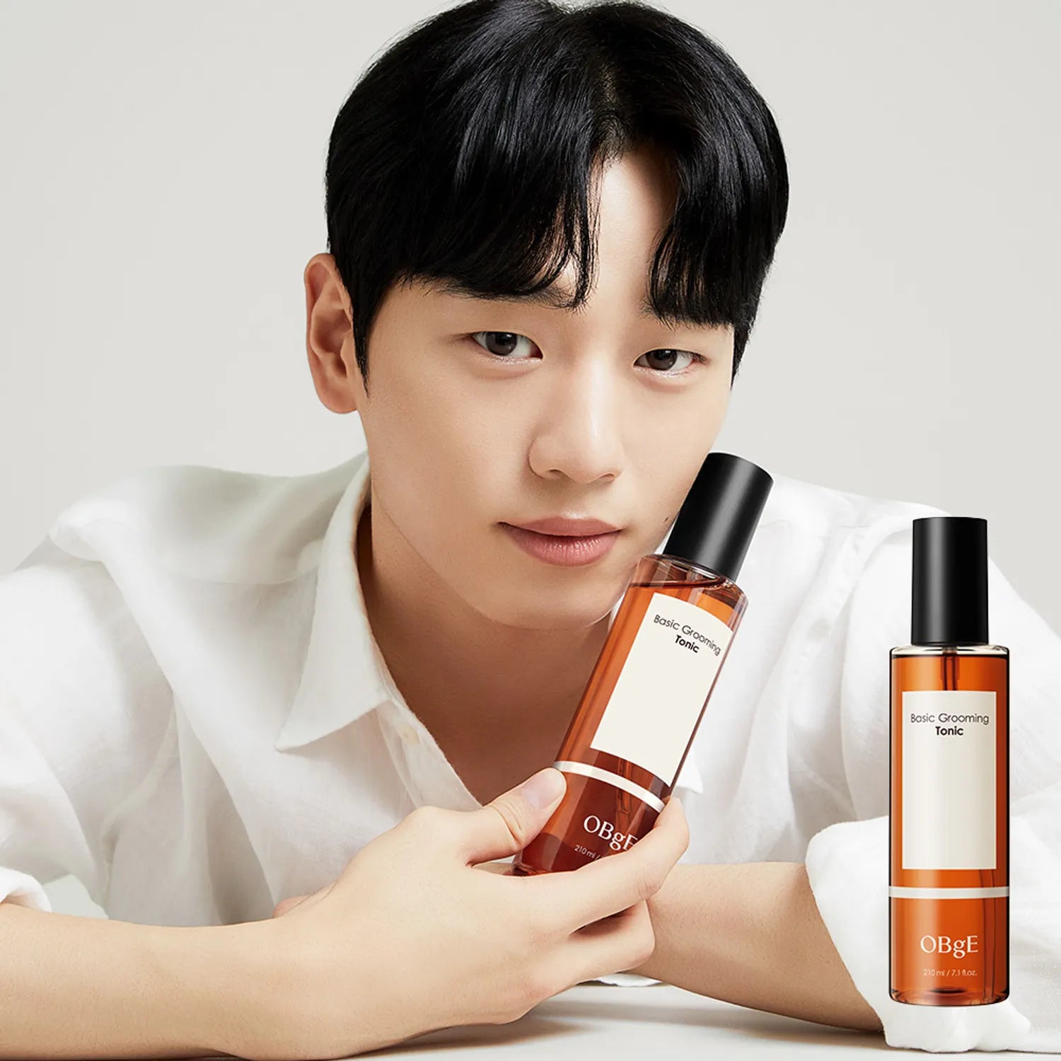 Gentleman Korea model holding OBGE Basic Grooming Tonic 210ml bottle in minimalist studio shot for men's skincare