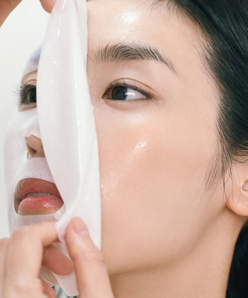Person applying ABIB Gummy Sheet Mask Heartleaf Sticker 10 sheets to face for skincare routine.