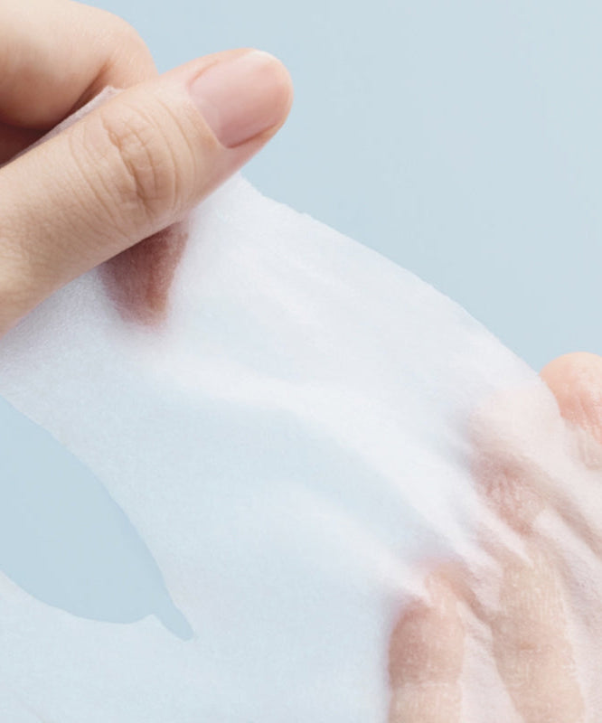 Close-up of hand holding ABIB Hyaluronic Acid Moisture Sheet Mask Essential Fit, showcasing its texture and quality.