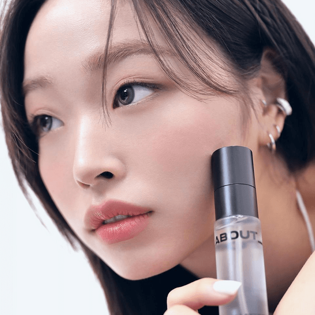 Model holding ABOUT TONE Long Lasting Makeup Coating Fixer showing flawless skin