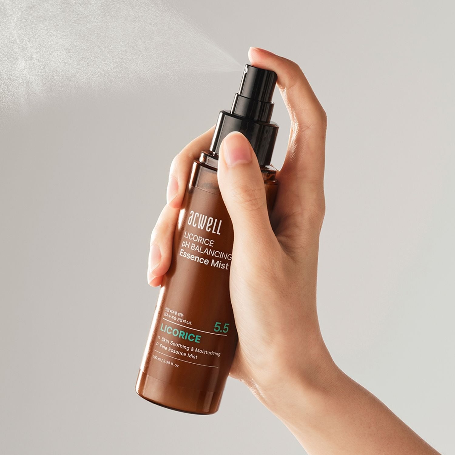 Hand holding ACWELL Licorice pH Balancing Essence Mist 100ml, showing product application.