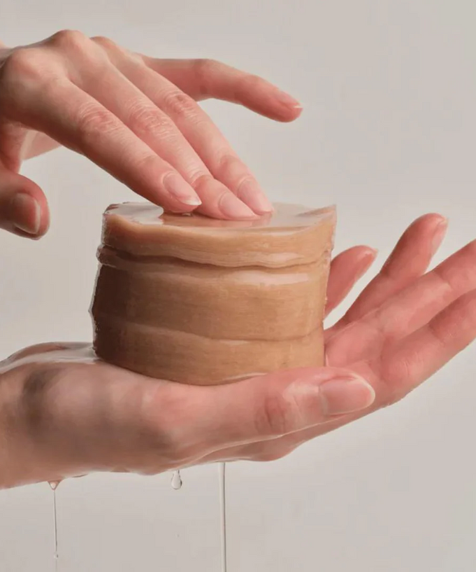 Hands holding a stack of ACWELL Licorice pH Balancing Toner Pad 70P with liquid dripping