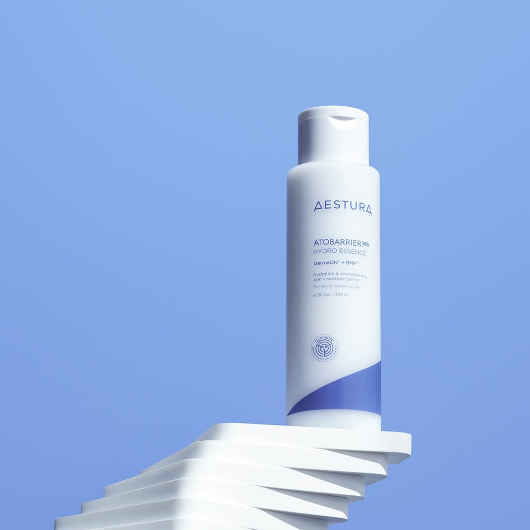 AESTURA Atobarrier 365 Hydro Essence 200ml bottle against a blue background, showcasing its sleek design and skincare branding.