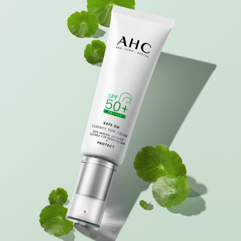 AHC Safe On Essence Sunscreen 50ml tube with SPF 50+, surrounded by green leaves for natural beauty protection.