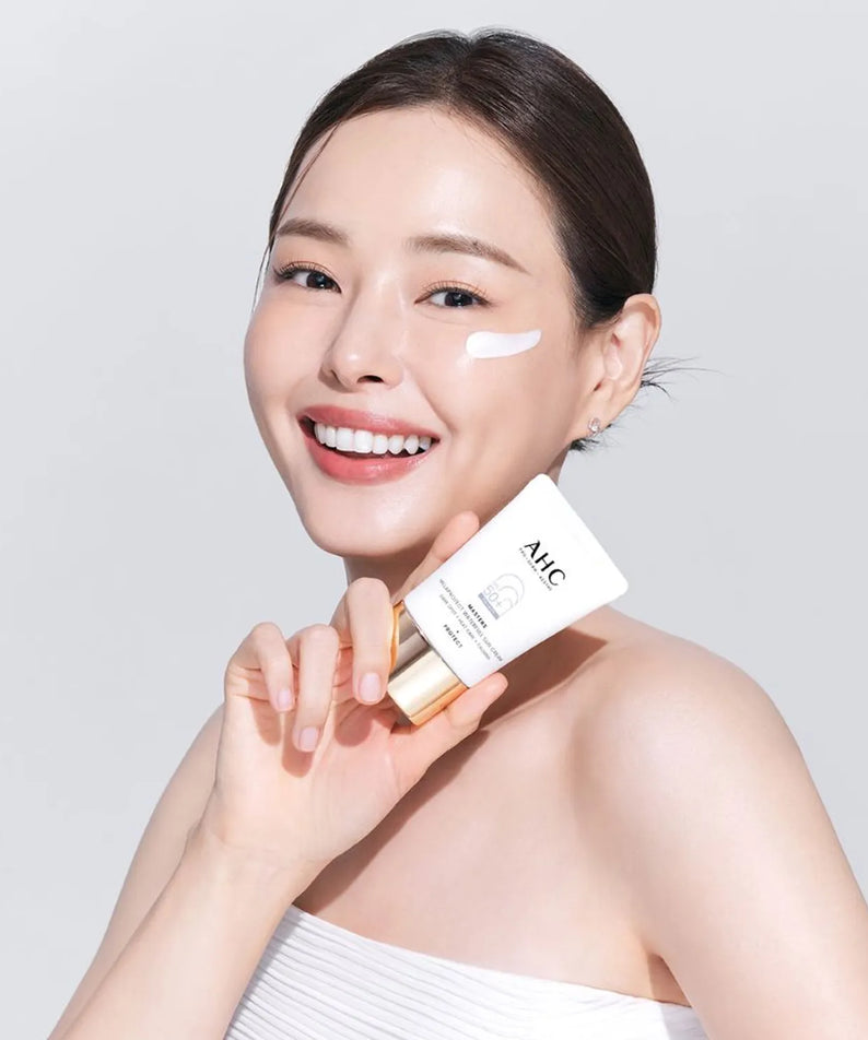 Person holding AHC Masters Mela Protect Waterfull Sunscreen 40ml, showing application of the product on cheek.