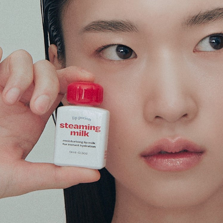 Close-up of a person holding a bottle of ALTERNATIVE STEREO Lip Potion Steaming Milk 9ml for instant hydration.