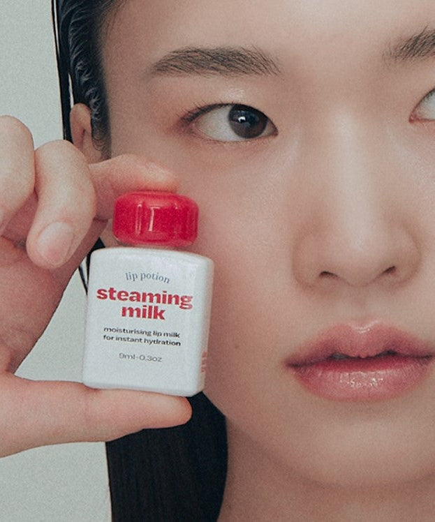Close-up of a person holding a bottle of ALTERNATIVE STEREO Lip Potion Steaming Milk 9ml for instant hydration.