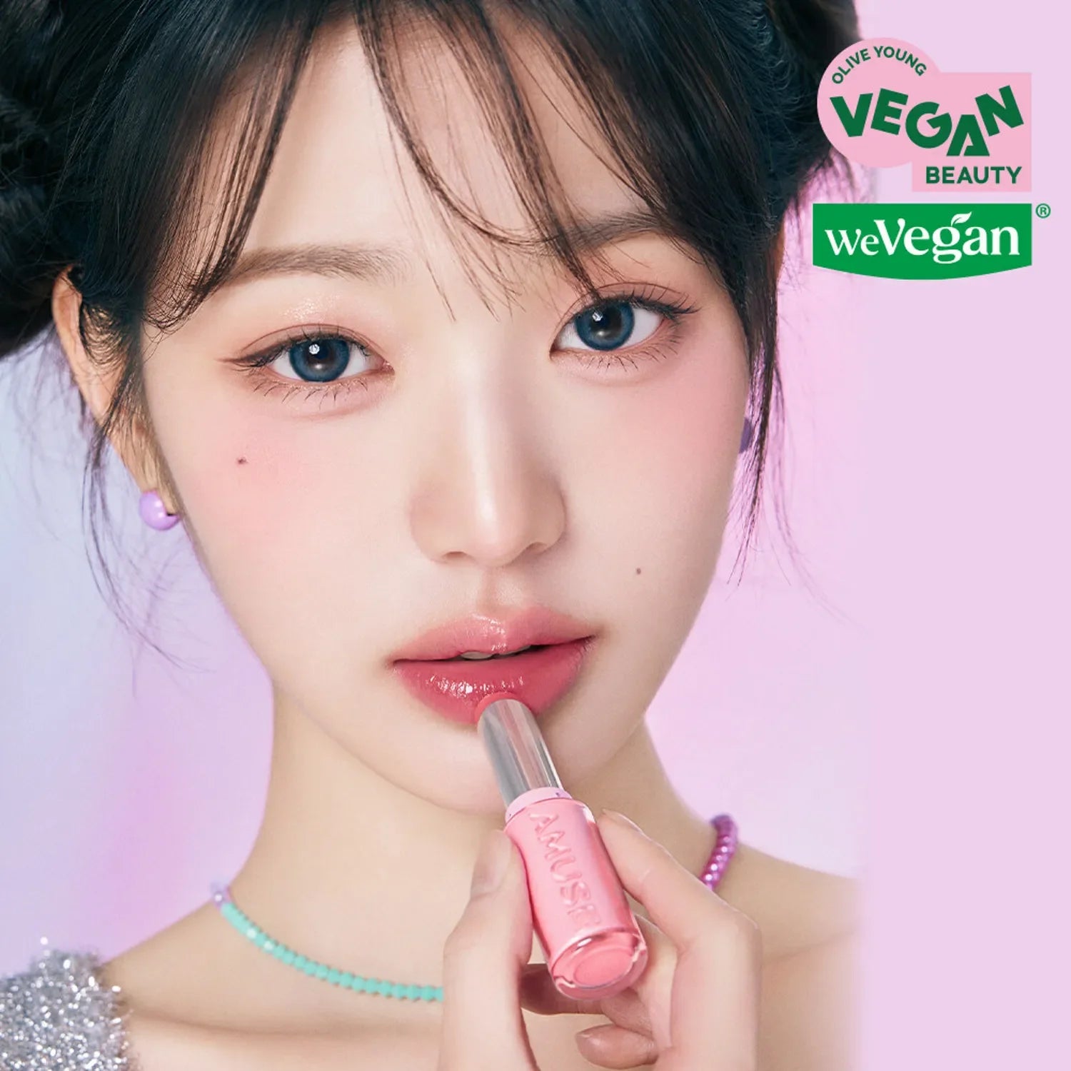 Model applying AMUSE Fondue Balm with a pink shade, highlighting its vegan beauty and smooth texture.