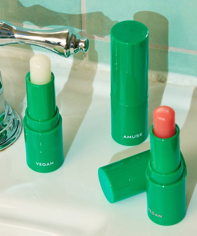 AMUSE Vegan Green Lip Balm displayed on a bathroom sink with open caps revealing product shades