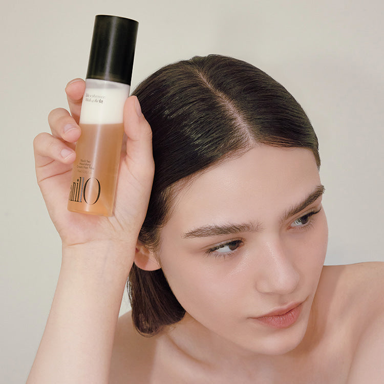 Model holding ANILLO Black Tea Nourishing Cream Hair Mist 70ml bottle near face