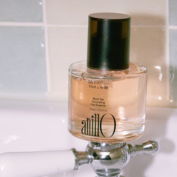 ANILLO Black Tea Nourishing Hair Essence 50ml bottle on sink by tiles