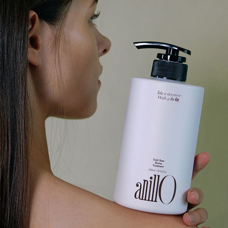 Woman holding ANILLO Dark Beer Biome Treatment 500ml bottle