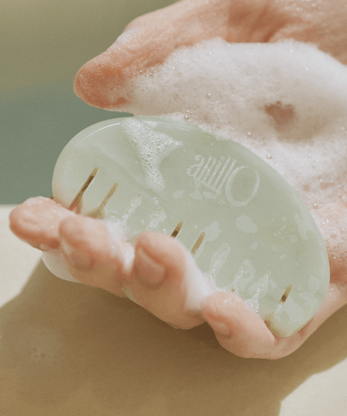 Hand holding a jade comb from ANILLO Special Scalp Care Set (Shampoo Bar & Jade GuaSha Comb), lathered with soap.