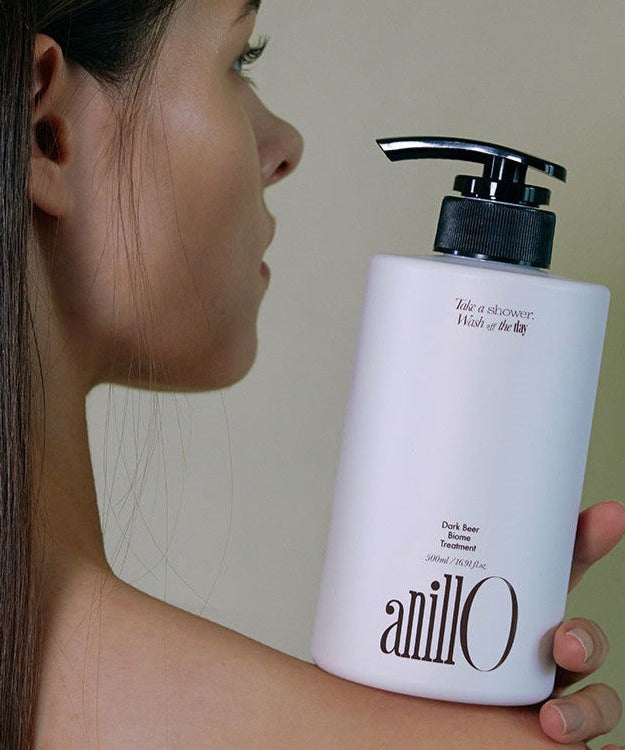 Woman holding ANILLO Dark Beer Biome Treatment 500ml bottle