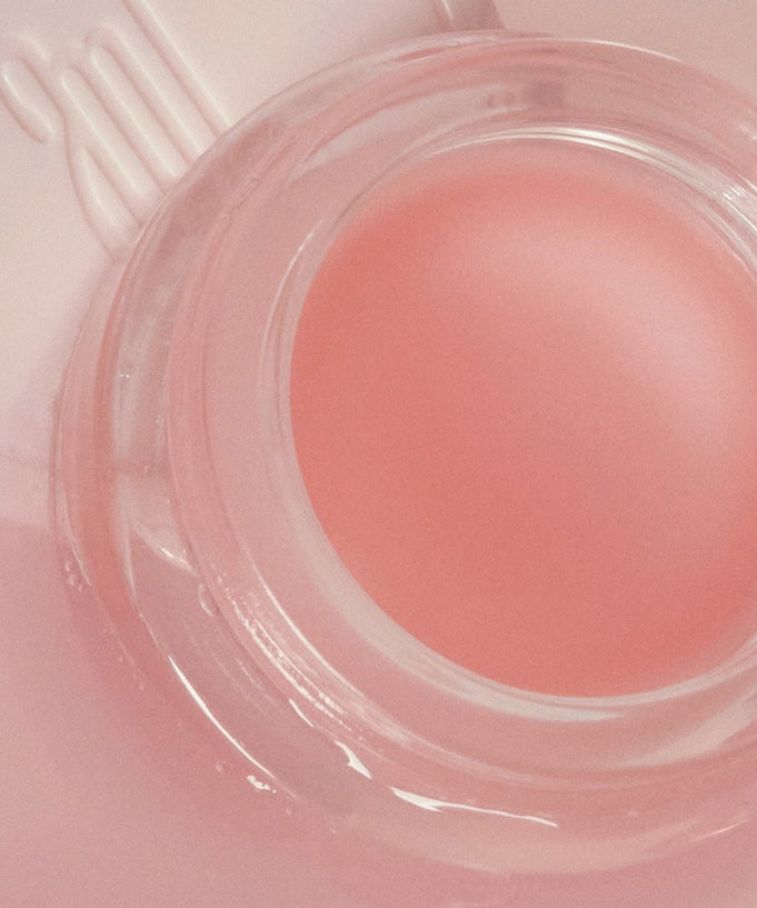 ANILLO Mellow Glow Balm in a clear container with a pink hue, offering moisturizing benefits and enhancing skin's natural glow.